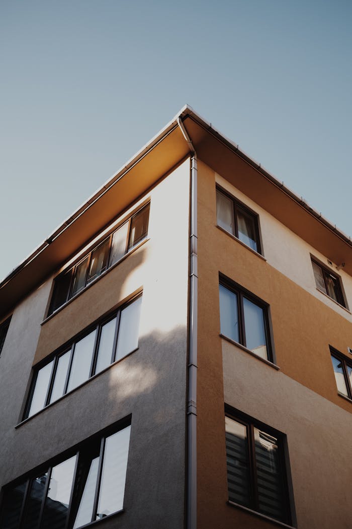 Low-angle view of a modern apartment building against a clear blue sky, showcasing contemporary architecture.
